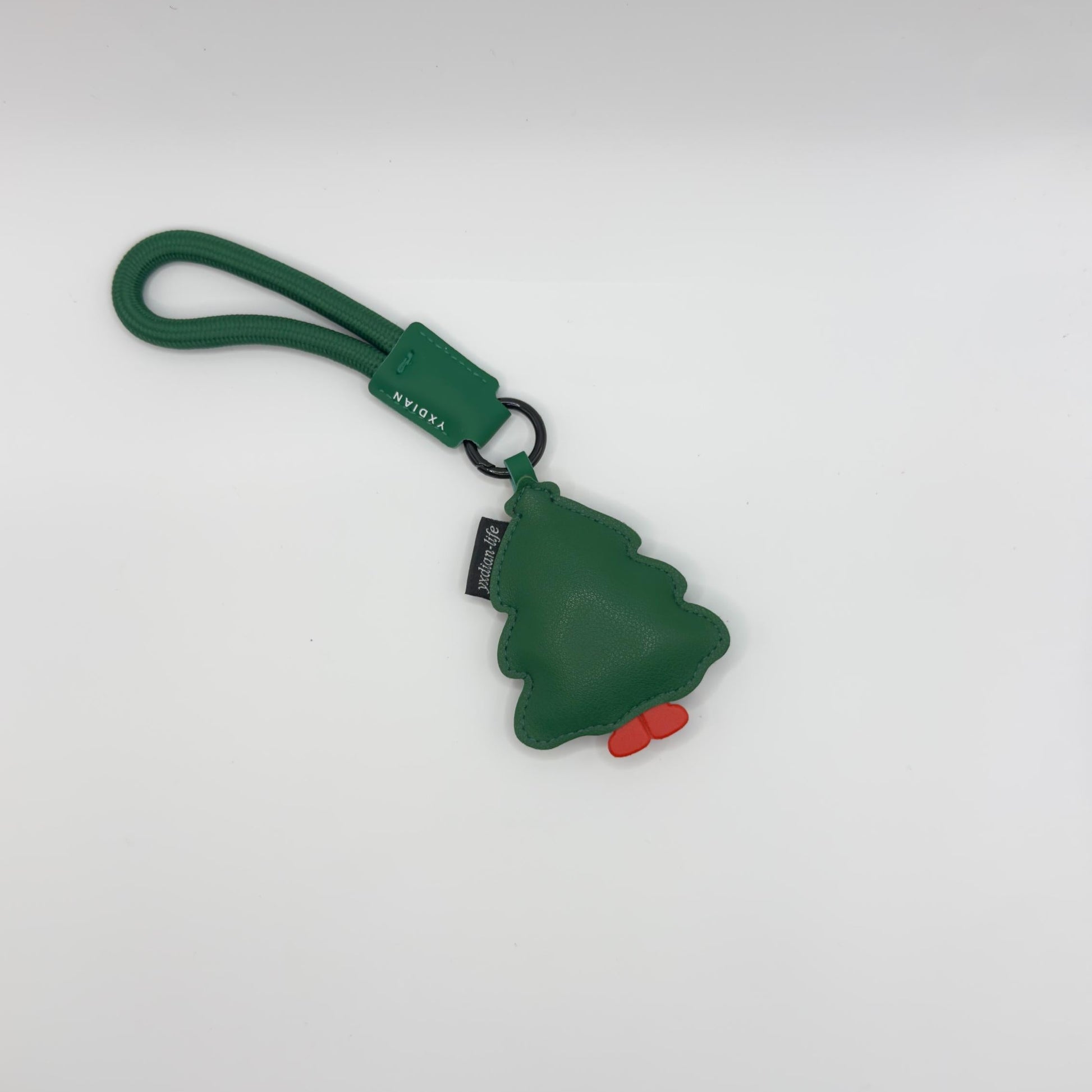Green pine tree-shaped keychain with a red dot on a white background