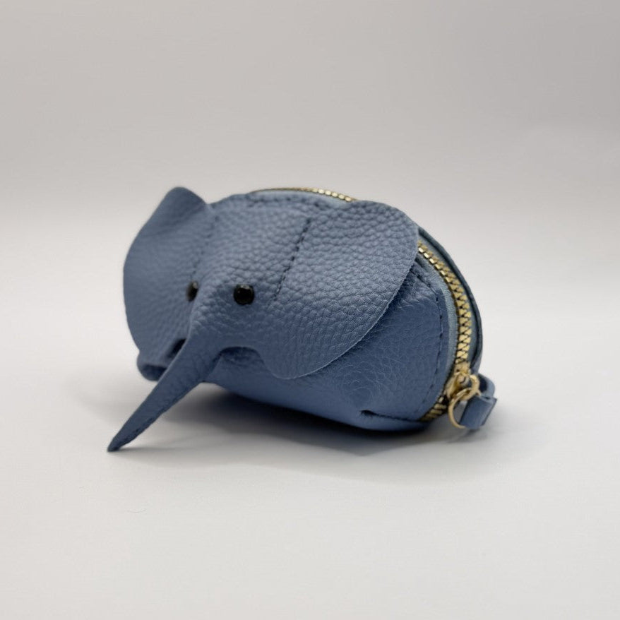 A small blue pebbled leather coin purse shaped like an elephant, featuring a gold-tone zipper and black embroidered eyes, set against a plain light gray background.