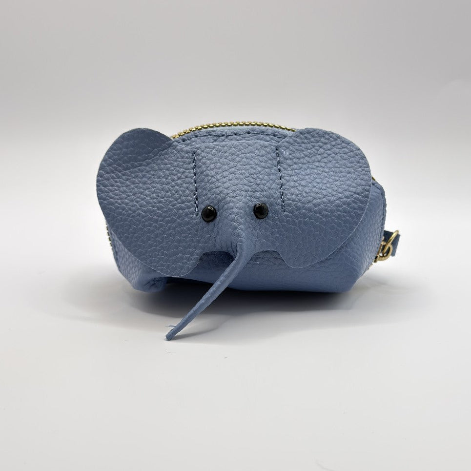 A light blue pebbled leather elephant-shaped coin purse with black bead eyes, a long trunk, and gold-tone zipper hardware, shown on a neutral light gray background.